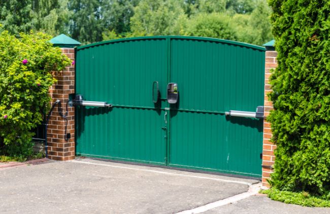 Motorised swing gate system installed by Auto Gate Guys, featuring green double gates and brick pillars for a secure driveway entrance